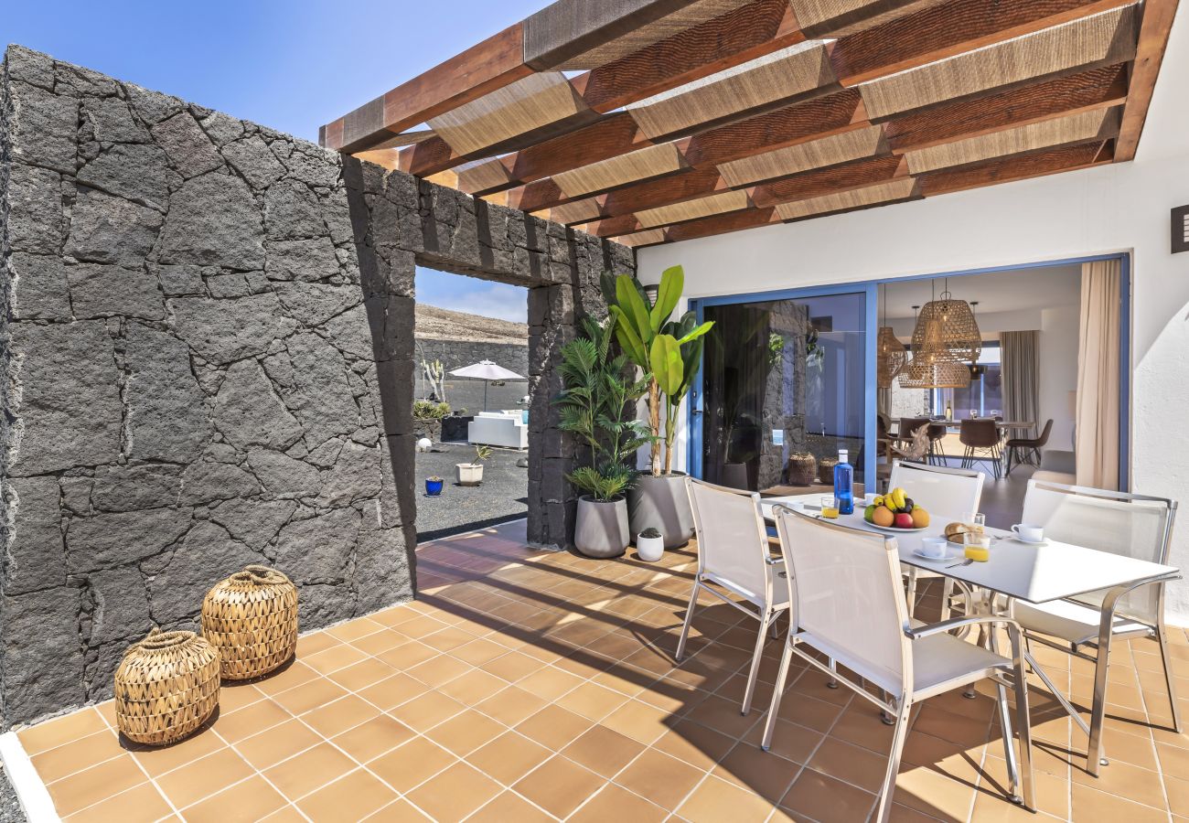 Zona exterior con pérgola de madera y suelo de piedra