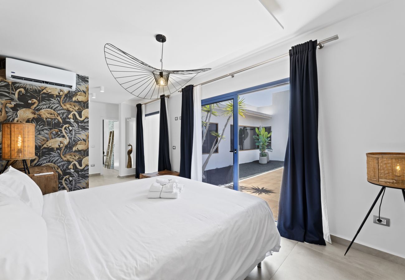 Cama doble con ropa blanca y pared acristalada