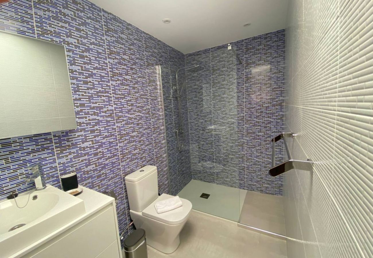 Baño con azulejos azules y ducha en Villa Marina Lanzarote