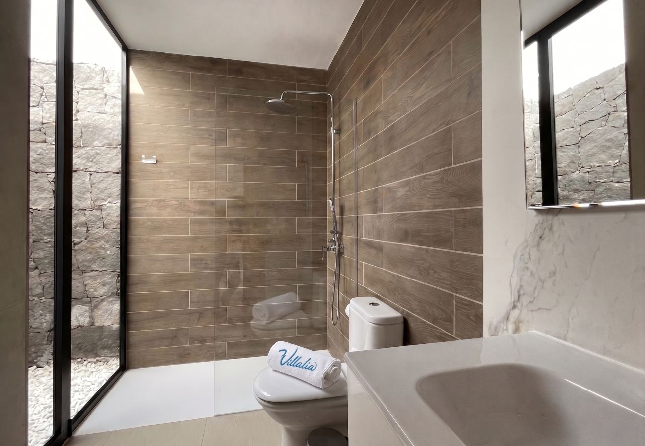 Bathroom with large window and stone wall views.